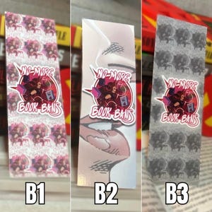 May include: Three different bookmark designs with the text "NO-MORE BOOK BANS" in a pink circle with a graphic of a person holding books. The first bookmark has a pink and white pattern, the second bookmark has a close-up of a mouth, and the third bookmark has a gray and white pattern.