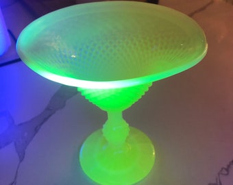 May include: A bright green glass bowl with a textured surface and a matching stem. The bowl is on a white surface.