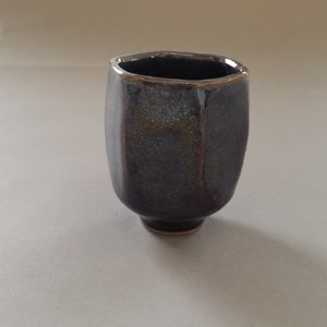 Puede incluir: Una taza de cerámica gris oscuro con forma hexagonal y un esmalte texturizado.