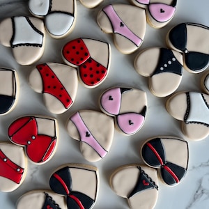 May include: Assortment of heart-shaped cookies decorated with various lingerie designs. The cookies feature different colors and patterns, including red, black, pink, white, and polka dots.