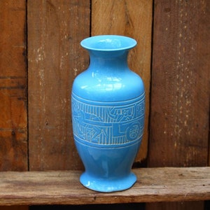May include: A blue ceramic vase with white geometric designs. The vase has a rounded base and a narrow neck.