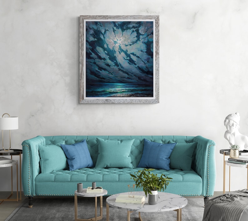 May include: A framed painting of a dark blue night sky with clouds and a bright moon shining through. The ocean is visible in the distance, with a beach in the foreground.