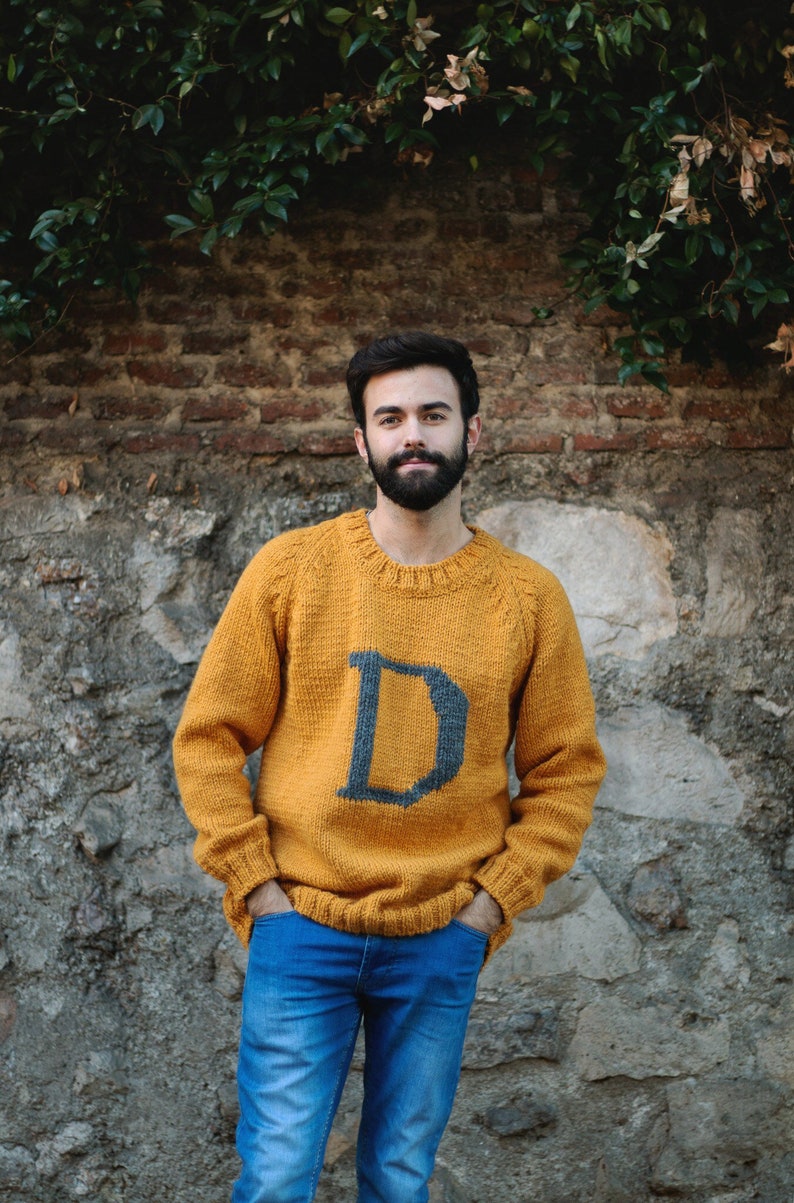 Boy wearing a mustard Magical Christmas Weasley sweater handwoven and personalized with a custom capital letter D on his chest