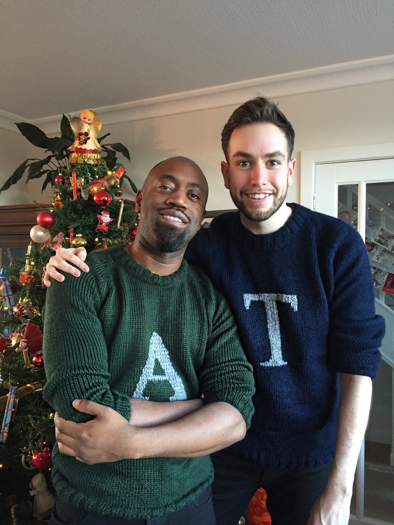 Men wearing a green Magical Christmas Weasley sweater with an A and other dark blue  handwoven jumper with personalized with a custom capital letter T on her chest