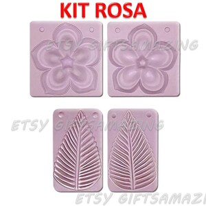 Puede incluir: Un juego de dos moldes de silicona para manualidades. Un molde presenta un dise&ntilde;o de flor, el otro un dise&ntilde;o de hoja. Los moldes son de color rosa y tienen las palabras "KIT ROSA" impresas en la parte superior.