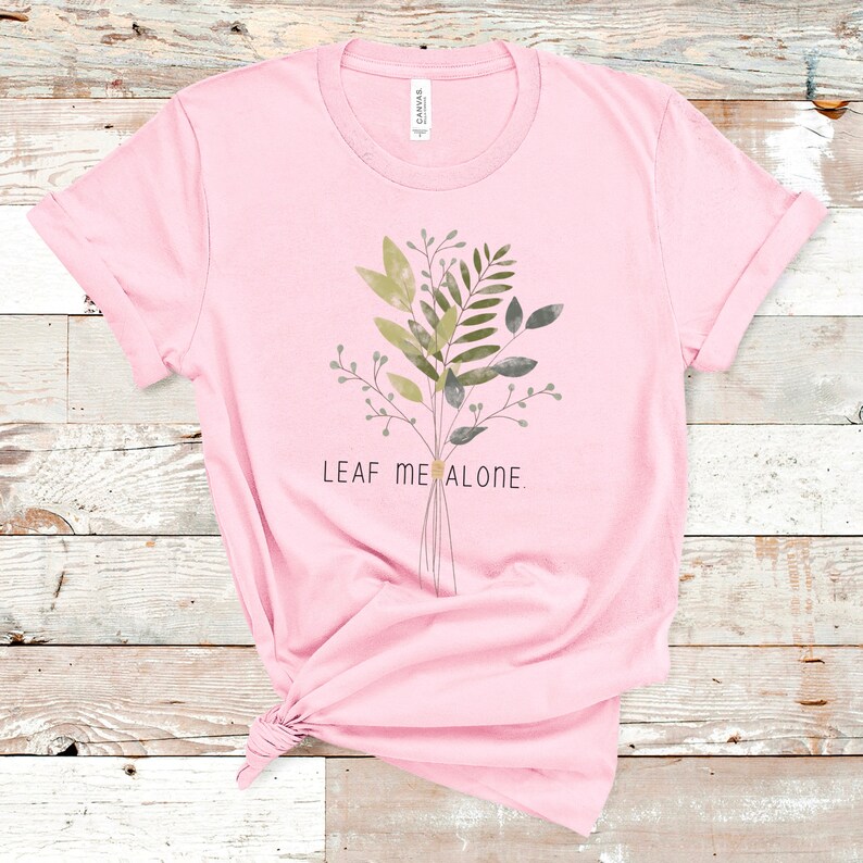 May include: Pink t-shirt with a green and gray floral design and the text "Leaf Me Alone."