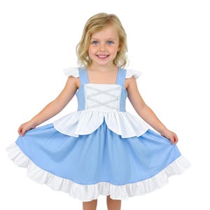 May include: A light blue and white dress with a square neckline and ruffled hem. The dress features a white bodice with silver criss-cross detailing and white flutter sleeves. The skirt is light blue with a white ruffle at the hem.