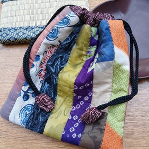Bolsa de kimono japonesa hecha a mano con cordón y retazos de tela, colorida y práctica.