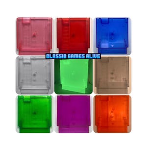 May include: A collection of nine rectangular video game cartridges in various translucent colors including pink, red, blue, clear, green, brown, bright green, purple, and orange. The text CLASSIC GAMES ALIVE is centered in blue pixelated font.