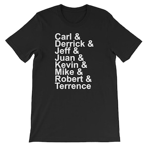 May include: Black t-shirt featuring the names Carl, Derrick, Jeff, Juan, Kevin, Mike, Robert, and Terrence in white. The names are listed vertically, separated by ampersands.