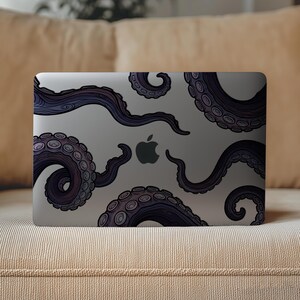 Op de afbeelding: Een laptop met een donkergrijze afwerking met een gestileerde illustratie van paarse octopus tentakels. De tentakels zijn over het oppervlak gerangschikt, met het Apple-logo in het midden.