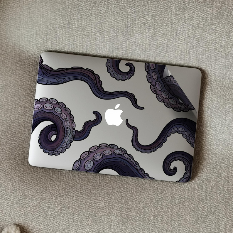 Op de afbeelding: Een laptop met een decoratieve skin met een paars en blauw octopus tentakel ontwerp. De tentakels zijn over het zilveren oppervlak gerangschikt, met het Apple-logo in het midden.