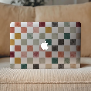 Op de afbeelding: Een laptop met een kleurrijk, geblokt patroon. Het ontwerp heeft vierkanten in tinten rood, oranje, geel, groen en grijs. Het Apple-logo is wit zichtbaar.