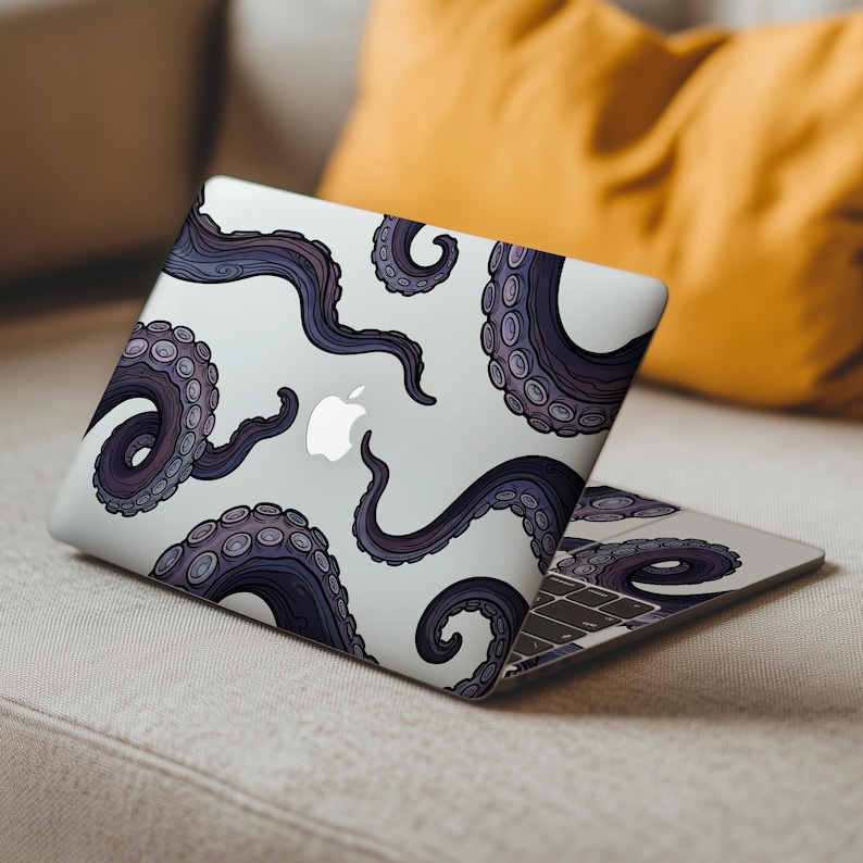 Op de afbeelding: Een witte laptop met een ontwerp van paarse en grijze octopus tentakels. De tentakels hebben gedetailleerde zuignappen en zijn verspreid over het oppervlak van de laptop. Het Apple-logo is zichtbaar. De laptop is open.