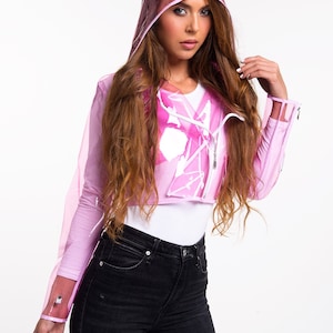 May include: A pink transparent raincoat with a hood. The raincoat has a zipper closure and white paint splatters on the front.