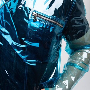 May include: A transparent blue jacket with zippered pockets. The jacket is made of a shiny, plastic-like material.