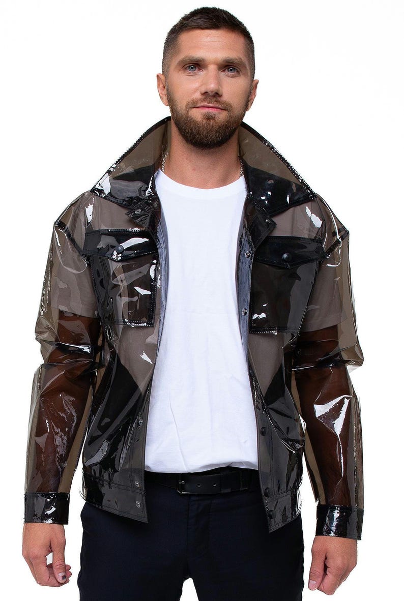 Pu&ograve; includere: Una giacca trasparente nera con chiusura a bottoni e tasche a patta. La giacca &egrave; realizzata in un materiale lucido, simile alla plastica.