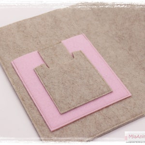 May include: A beige felt pouch with a pink felt pocket. The pouch has a flap that closes with a snap.