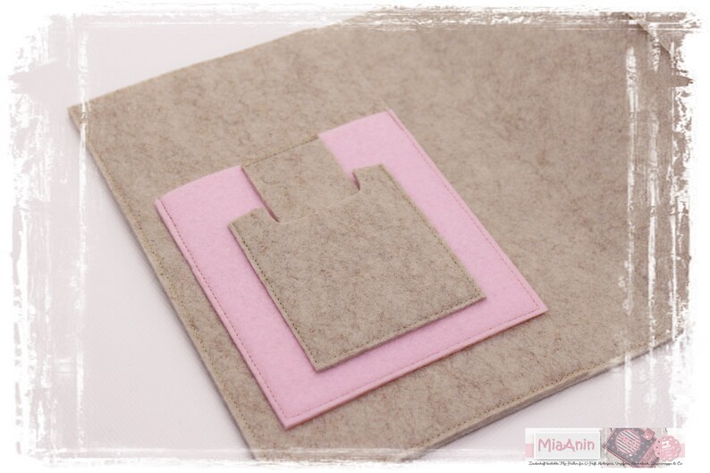 May include: A beige felt pouch with a pink felt pocket. The pouch has a flap that closes with a snap.