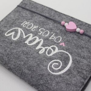 Pu&ograve; includere: Borsa in feltro grigio con ricamo bianco che dice "Our So & So" con un cuore rosa e una corda di perline rosa e bianca.