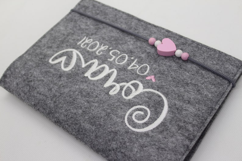 Pu&ograve; includere: Borsa in feltro grigio con ricamo bianco che dice "Our So & So" con un cuore rosa e una corda di perline rosa e bianca.