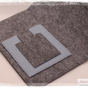 May include: A grey felt pouch with a smaller grey felt pocket inside. The pouch has a flap that folds over the pocket.