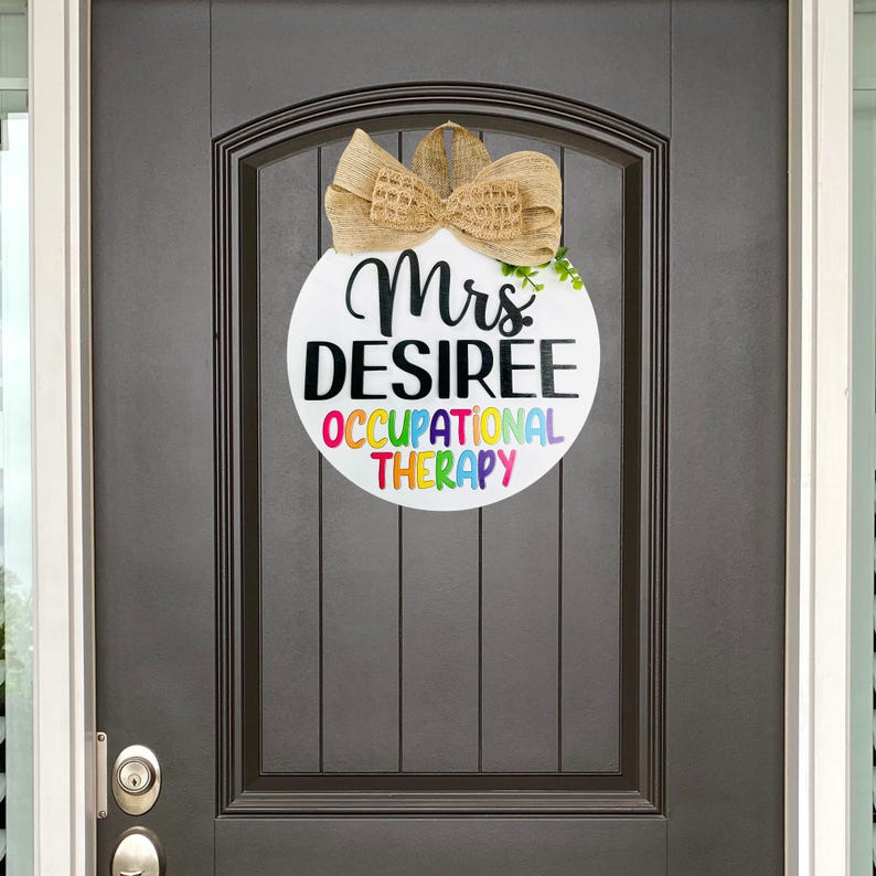 May include: A white round door hanger with a brown burlap bow and the text "Mrs. Desiree Occupational Therapy" in rainbow colors.