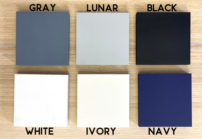 May include: Six paint color swatches on a wood surface. The colors are: Gray, Lunar, Black, White, Ivory, and Navy.