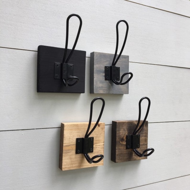 K&ouml;nnte beinhalten: Vier Wandhaken aus Holz mit schwarzen Metallhaken. Die Haken sind quadratisch und in vier verschiedenen Holzarten erh&auml;ltlich: Schwarz, Grau, Naturholz und Dunkelbraun.