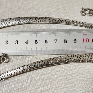 May include: Two silver-toned metal bookmarks featuring a dragon head design with a textured scale pattern along the body. A metal ruler is positioned between the bookmarks, showing a length of approximately 12 centimeters for each item.