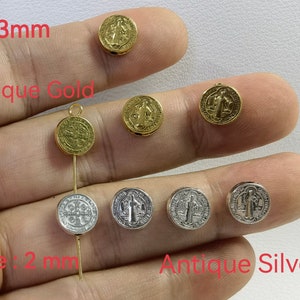 May include: Antique gold and silver charm pendants with a religious design. The charms are 9x3mm and have a 2mm hole.