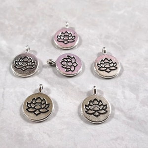 May include: Six silver-toned metal charms with a lotus flower design. The charms are round and have a loop at the top for attaching to jewelry or other crafts.