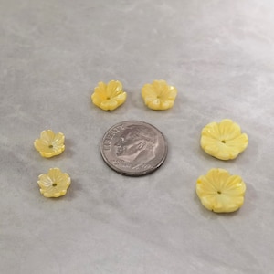 May include: Six yellow flower-shaped buttons with a hole in the center. The buttons are made of a smooth, shiny material.