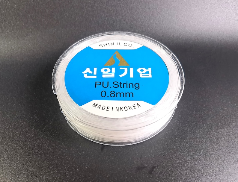 May include: A spool of white PU string, 0.8mm thick, made in Korea. The label reads "Shin Il Co. 신일기업 PU.String 0.8mm MADE IN KOREA".