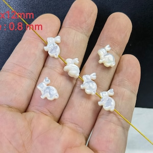 Puede incluir: Seis abalorios de conejo de madreperla blanca con un agujero para encordar. Los abalorios miden aproximadamente 11 mm x 12 mm y tienen un tamaño de agujero de 0,8 mm.