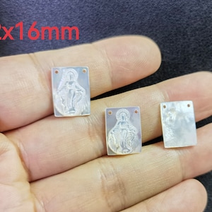 Può includere: Tre ciondoli rettangolari in madreperla bianca con un'immagine in rilievo della Vergine Maria. I ciondoli misurano 12 mm per 16 mm.