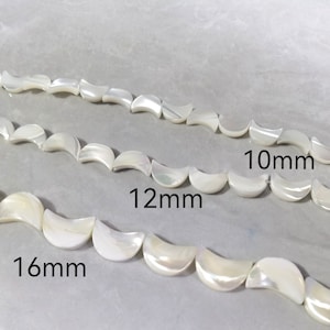 Può includere: Tre fili di perle di madreperla bianca a forma di mezzaluna. Le perle sono disposte in file, con le perle più grandi in basso e le più piccole in alto. Le perle sono etichettate con la loro dimensione in millimetri: 16 mm, 12 mm e 10 mm.