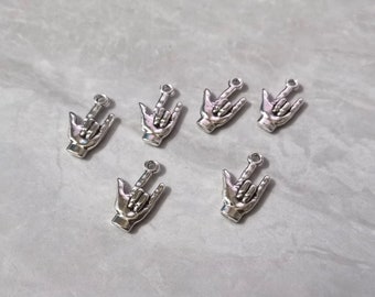 Puede incluir: Seis dijes de metal en tono plateado, cada uno con forma de mano haciendo el signo de te amo en el lenguaje de señas americano. Cada dije cuenta con un pequeño lazo circular en la parte superior para sujetarlo, con un acabado pulido y contornos de dedos detallados.