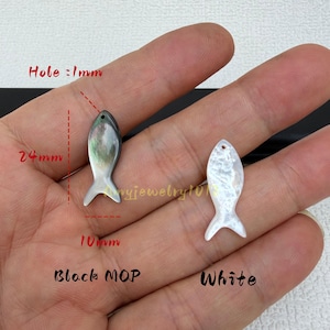 May include: Two fish-shaped charms made of mother of pearl, one black and one white. The black charm measures 24mm in height and 10mm in width, with a 1mm hole. The white charm has a similar fish silhouette with a small hole at the top.