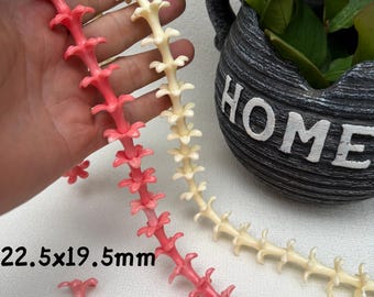 May include: Two strands of decorative floral chain in coral and cream colors. The coral chain is held in a hand, with loose flower accents. The text "22.5x19.5mm" is visible. A decorative pot with the word "HOME" is in the background.