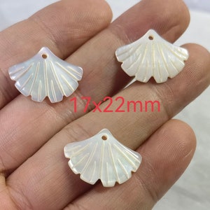 Op de afbeelding: Drie witte parelmoer schelp hangers in de vorm van een waaier met een gat aan de bovenkant om te rijgen. De hangers meten 17 x 22 mm.