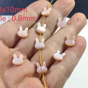 May include: A strand of pink shell beads with a bunny rabbit design. The beads are 8mm by 10mm with a 0.8mm hole.
