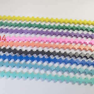 Puede incluir: Nueve hebras de cuentas con forma de cruz en varios colores, incluyendo amarillo, verde, morado, rosa, naranja, negro, azul y turquesa. Las hebras están numeradas del 01 al 09.