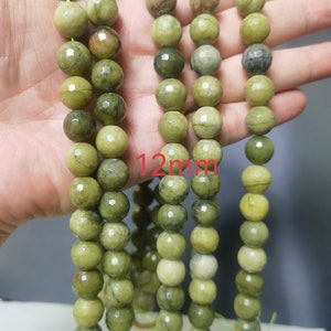 May include: A strand of green gemstone beads, each bead is faceted and measures 12mm in diameter. The beads have a mottled green color with darker green veins running through them.