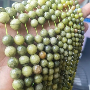 May include: A strand of green and yellow gemstone beads, strung on a thin green thread. The beads are round and have a smooth, polished finish.