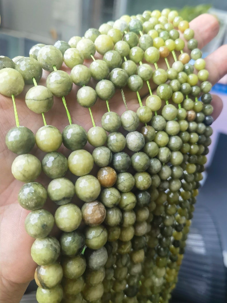 May include: A strand of green and yellow gemstone beads, strung on a thin green thread. The beads are round and have a smooth, polished finish.