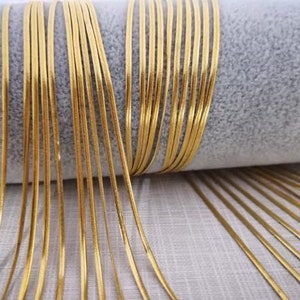 May include: A close-up of a bundle of gold-colored chain links. The chain links are thin and have a shiny finish.