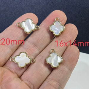 May include: Four gold-tone clover charms with white mother-of-pearl centers. The charms are 14x20mm and 16x14mm.