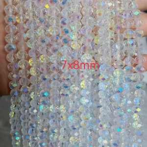 Może przedstawiać: Zbliżenie na sznury przezroczystych, fasetowanych koralik&oacute;w z opalizującymi refleksami. Koraliki, o wymiarach około 7x8mm, są nawleczone. Idealne do tworzenia biżuterii lub projekt&oacute;w rzemieślniczych.