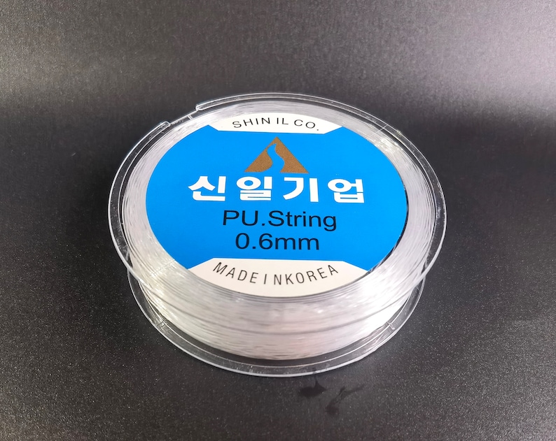 May include: A spool of clear, white, 0.6mm PU string, labeled "Shin Il Co. 신일기업 PU.String 0.6mm MADE IN KOREA".